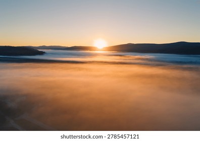 Warm sunlight illuminates a thick layer of golden fog blanketing a wide valley at sunrise
