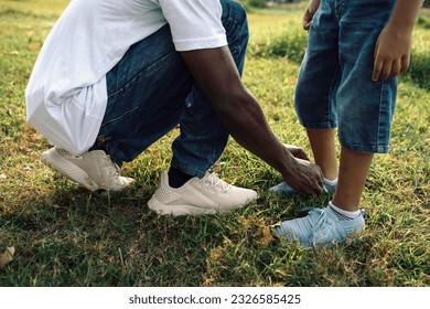 Warm Sunny Day in the Park: African American Father Assists Son in Tying Shoe Lace - Powered by Shutterstock