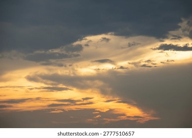 Warm sunset light breaks through layered clouds, creating a dramatic sky with soft golden tones and moody atmosphere, perfect for backgrounds, nature themes, and peaceful evening concepts.