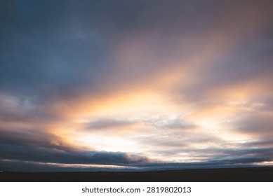 Warm sunset light breaks through heavy clouds above the remote Icelandic highlands, creating a dramatic and colorful evening cloudscape