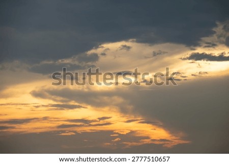 Warm sunset light breaks through layered clouds, creating a dramatic sky with soft golden tones and moody atmosphere, perfect for backgrounds, nature themes, and peaceful evening concepts.