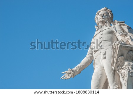Warm sunset over Mozart monument in front of Palmenhaus, near Neue Burg and Hofburg Palaces garden, in historical downtown of Vienna, Austria at sunny day, blue sky with copy space for text