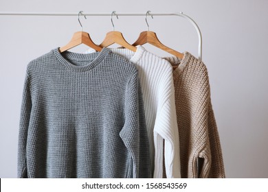 Warm sweaters on a wardrobe hanger on a light background. Autumn, winter clothes.
 - Powered by Shutterstock