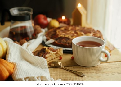 Warm tea in stylish cup on rustic wooden table with freshly baked apple pie with cinnamon, candle, autumn leaves, pumpkins and nuts. Autumn hygge still life. Atmospheric cozy home - Shutterstock ID 2208318935