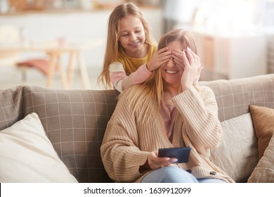 Warm Toned Portrait Of Cute Girl Playing Peek A Boo With Mom While Surprising Her On Mothers Day, Copy Space