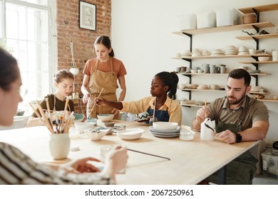 Warm toned portrait of diverse group of people decorating ceramics in pottery workshop, copy space - Powered by Shutterstock