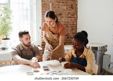 Warm toned portrait of group of people enjoying pottery class in cozy studio - Powered by Shutterstock