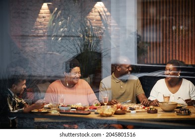 Warm Toned Portrait Of Happy African-American Family Enjoying Dinner Together At Terrace Behind Glass Wall