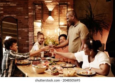 Warm Toned Portrait Of Happy African-American Family Clinking Glasses And Toasting While Enjoying Dinner Together At Evening