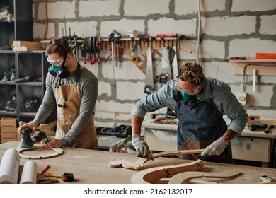 Warm Toned Portrait Of Two Carpenters In Protective Gear Working With Wood While Building Handicraft Furniture In Workshop