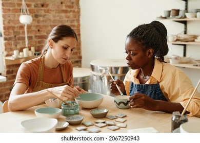 Warm toned portrait of two young women enjoying pottery workshop in cozy studio, copy space - Powered by Shutterstock