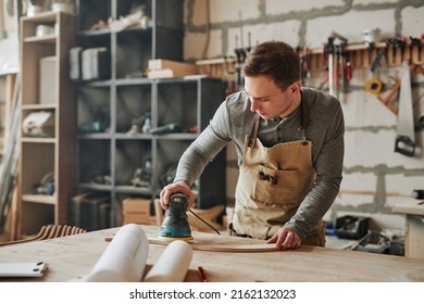 Warm toned portrait of young carpenter sanding wood and building handmade furniture piece in workshop, copy space - Powered by Shutterstock