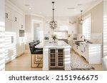 Warm white kitchen with expansive countertops island high end appliances spice kitchen black leather chair dining table wine fridge and office work station
