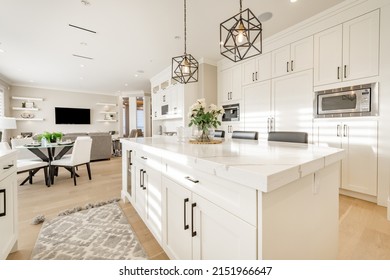 Warm white kitchen with expansive countertops island high end appliances spice kitchen black leather chair dining table wine fridge and office work station - Shutterstock ID 2151966647