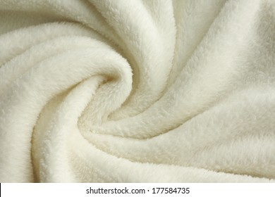 A Warm, White, Plush Micro Fleece Blanket Fabric Is Swirled Into A Circular Pattern Background