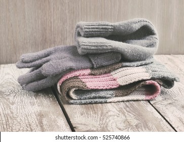 Warm winter knitted clothes - hat, scarf, gloves on a wooden background, female, selective focus, vintage toning