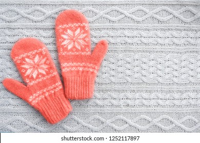 Warm woolen mittens on knitted background. Living coral creative and moody color of the picture. Color of the 2019 year.