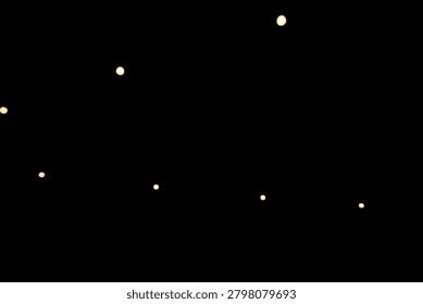 Warm yellow bokeh string lights hanging on a wire against dark night background. Blurry light bulbs backdrop for romantic cafe, garden party, or festive decoration
