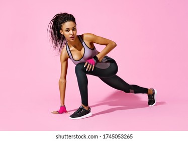 Warming Up Before Training. Photo Of African American Girl In Black Sportswear On Pink Background. Strength And Motivation