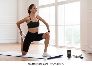 Warming Up Before Workout. Smiling Sporty Woman Training At Home Or Fitness Club Studio, Beautiful Female Stretching Legs After Exercises On Yoga Mat, Wearing Black Bra And Bike Shorts - Powered by Shutterstock