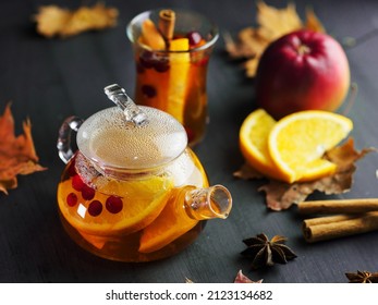 Warming fruit tea in a teapot with cinnamon. Slices of orange, apple and cranberries. Sliced fruit