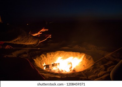 Warming hands over a bonfire while roasting marshmallows
