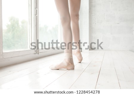 Warming stretch for the ballerina's feet at the big window before the lesson
