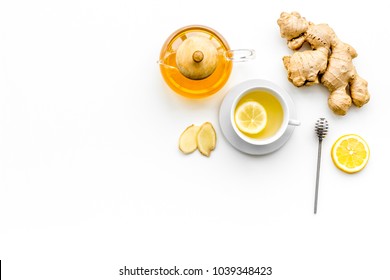 Warming tea with lemon and ginger. Cup, teapot, ginger root on white background top view copy space