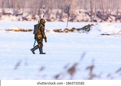 A Warmly Dressed Man With Ice Fishing Gear Returns From A Fishing Trip