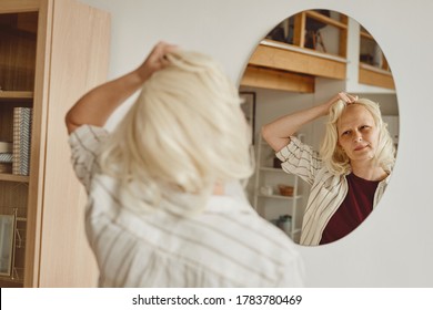 Vue arrière réchauffée portrait d'une femme chauve enlevant une perruque tout en regardant dans un miroir à l'intérieur de la maison, alopécie et conscience du cancer, espace de copie