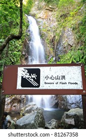 Warning Board Of Flash Flood Infront Of Waterfall