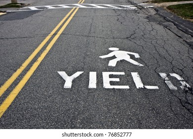 Warning at crossroad saying yield and person sign on asphalt