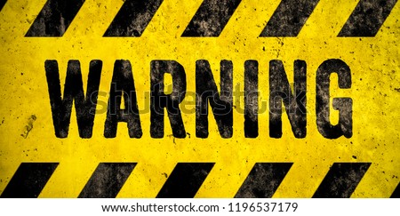 WARNING danger sign word text as stencil with yellow and black stripes painted over concrete wall cement texture wide banner background. Concept image for caution, dangerous area and hazard.