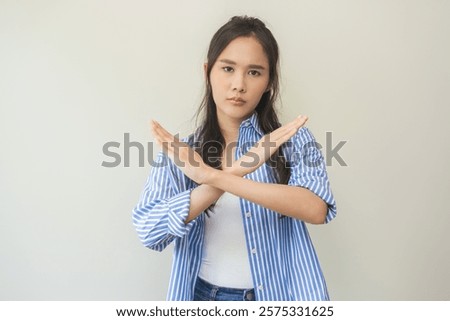 Warning expression negative and serious on face. Asian young woman, female stand making stop, showing gesture hands, doing symbol deny with palm isolated on background at home, perspective forbidden.