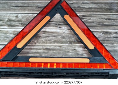 A Warning Foldaway Reflective Road Hazard Warning Triangle Isolated On Wooden Background, A Safety Measure When A Car With A Breakdown Alongside The Road, Selective Focus Of Red Triangle Warning Sign