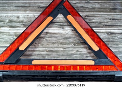 A Warning Foldaway Reflective Road Hazard Warning Triangle Isolated On Wooden Background, A Safety Measure When A Car With A Breakdown Alongside The Road, Selective Focus Of Red Triangle Warning Sign