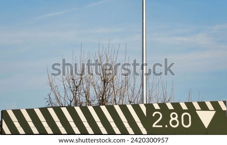 Warning road sign max height 2.80 m. Bright colors and white warning stripes, in public parking structure. Maximum height clearance. Clear sky background. Winter season