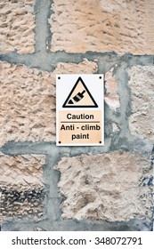 A warning sign for anti-climb paint on the wall of a building