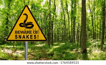 Warning sign beware of Snakes in infested area in the green forest 