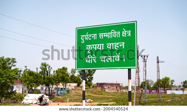 Warning sign board\
with written Hindi Language. Road sign board to aware people to go\
slowly in populated\
area.