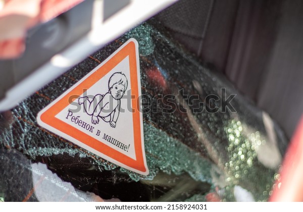 Warning sign of children\
inside a car after an accident with bloody broken glass.\
Translation: Child in the car. Close-up of white baby on board\
sticker on car back\
window
