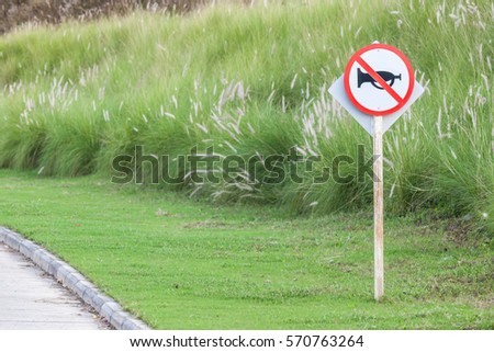 The warning sign do not use vehicle horn with flowering grass background of green golf course objective for do not disturbing golf players.