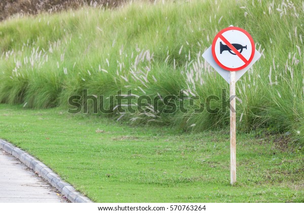 The warning sign do not use vehicle horn
with flowering grass background of green golf course objective for
do not disturbing golf
players.