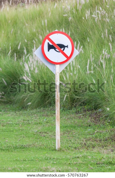 The warning sign do not use vehicle horn\
with flowering grass background of green golf course objective for\
do not disturbing golf\
players.