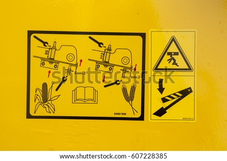 Warning sign on agricultural machinery. Before performing work under the inclined chamber and reel, it is necessary to fix the lifting cylinders with the help of the existing locking elements