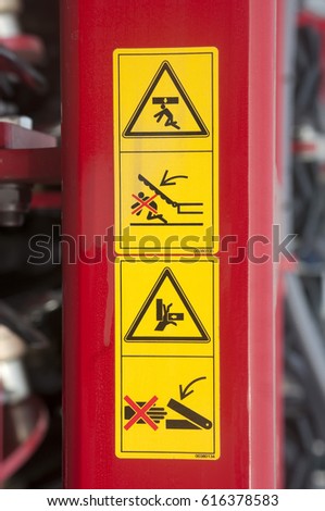 Warning sign on agricultural machinery. Before working under the sloping chamber is necessary to fix the lifting cylinders. Caution possible damage to the hand. Be careful.