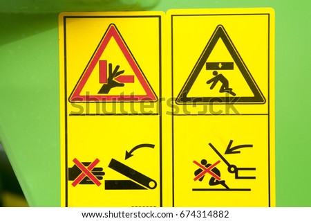 Warning sign on agricultural machinery. Before working under the sloping chamber is necessary to fix the lifting cylinders. Caution possible damage to the hand. Be careful.