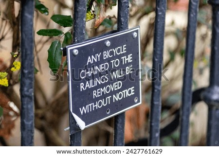 A warning sign on the fence railings outside some block of flats banning the chaining of bicycles to it.