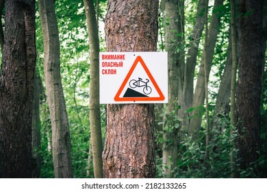 Warning sign on russian language:  Warning, steep slope. Cyclist Caution, steep slope and slow down warning sign on a countryside track.