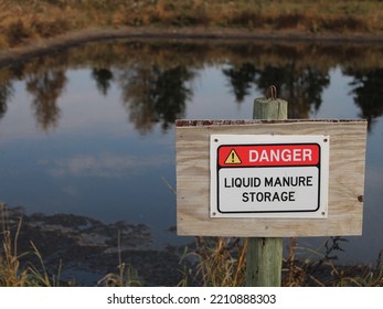 A Warning Sign Posted At The Edge Of A Large Livestock Manure Storage Lagoon